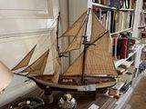 a model of a sailboat on a table in front of a bookshelf
