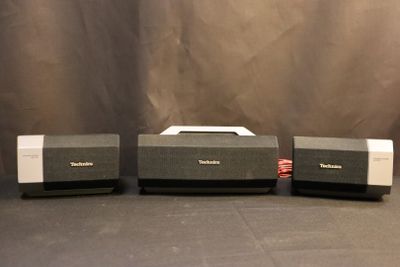 three speakers sitting on top of each other on a black surface