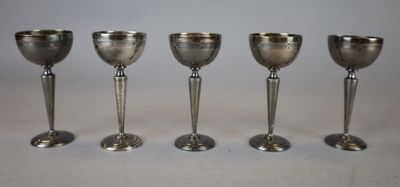 four silver goblets are lined up in a row on a table