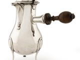une cafetière ancienne en argent avec une poignée en bois sur un support