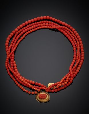 un gros plan sur un collier de perles rouges muni d'un fermoir doré
