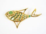 une image représentant une broche en forme de poisson doré et vert sur fond blanc