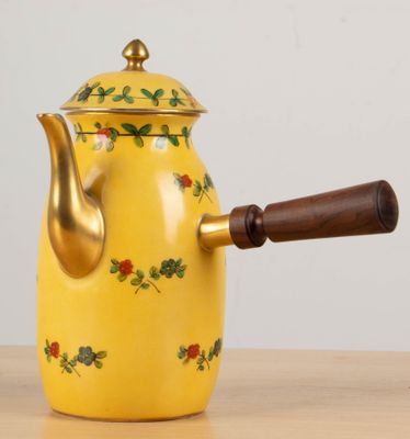 a yellow tea pot with a wooden handle on a table