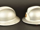two white hard hats sitting on top of each other on a table