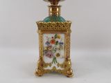 a small gold and green vase with flowers on it