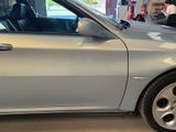 a silver car parked in a garage with a man in the background