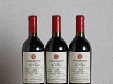 trois bouteilles de vin posées sur une table en bois à côté d'une horloge