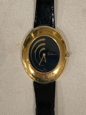 une montre noire et dorée posée sur un tissu blanc