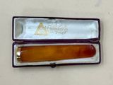 an orange comb in a purple case on a white table