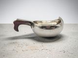 a small silver bowl with a handle on a table