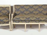 two chairs and a couch in a room with a white wall