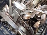 a lot of silver spoons and forks in a basket