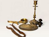 brass candlesticks and other brass objects on a white background