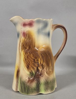 a small pitcher with a rooster on it on a table