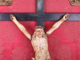 a statue of jesus on a cross on a red wall