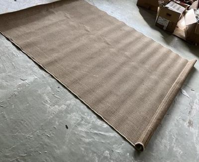 un tapis marron posé par terre, à côté d'une pile de cartons