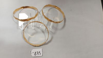 trois bagues en or posées sur une table blanche, avec une étiquette de prix