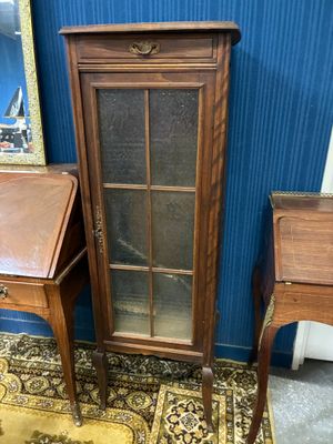 une armoire en bois avec une porte vitrée, à côté d'une petite table