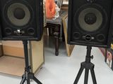 une paire d'enceintes posées sur un trépied dans une pièce