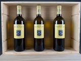 three bottles of wine sit in a wooden box on a table