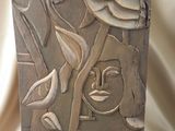 sculpture représentant un visage sur un bloc de pierre, ornée de feuilles et de fleurs