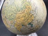 a small globe on a metal stand with a picture frame in the background
