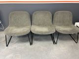 three grey chairs with black legs in front of a gray wall