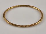 gros plan d'un bracelet en or sur une surface blanche