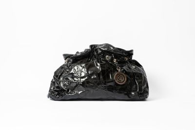 un gros plan d'un sac à main noir posé sur une surface blanche