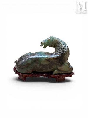 statue d'un cheval couché sur un morceau de bois posé sur une surface blanche