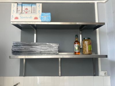une étagère en métal sur laquelle sont posées quelques bouteilles et assiettes