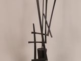 a black sculpture of sticks sticking out of a vase on a white surface