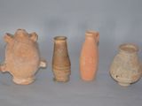 quatre vases en argile sont alignés sur une surface grise