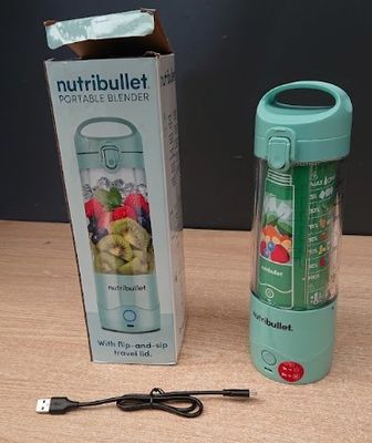 un mixeur posé sur une table à côté d'une corbeille de fruits