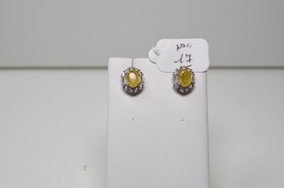 une paire de boucles d'oreilles jaunes et blanches posées sur un présentoir blanc
