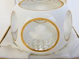 une théière blanche bordée d'or posée sur une nappe blanche