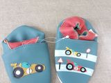 pair of baby shoes with cars on them sitting on a couch
