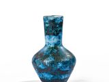 un vase bleu posé sur une surface blanche