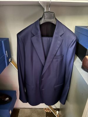 un costume bleu suspendu à un cintre dans une armoire