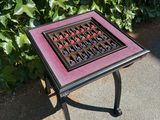 a small table with a chess board on it in front of a bush