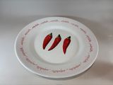 two red chili peppers on a white plate on a table