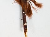 a brown feather on a white surface next to a pair of chopsticks