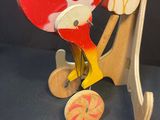 a wooden toy of a parrot on a wooden stand