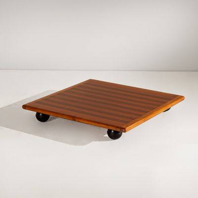 une image représentant une petite table en bois munie de roulettes, posée sur une surface blanche