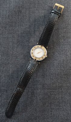 un gros plan d'une montre-bracelet posée sur une surface grise