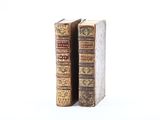 two old books are sitting side by side on a white surface