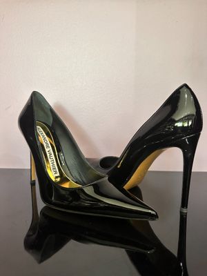 black high heeled shoes on a black table with a white wall in the background