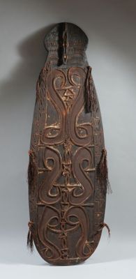 un vase brun orné d'un motif sur une surface blanche