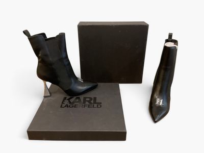 une paire de bottines en cuir noir exposée devant une boîte noire