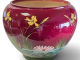 a red vase with yellow flowers painted on it